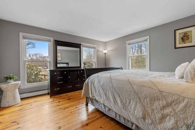 bedroom with light wood-style flooring and a baseboard heating unit