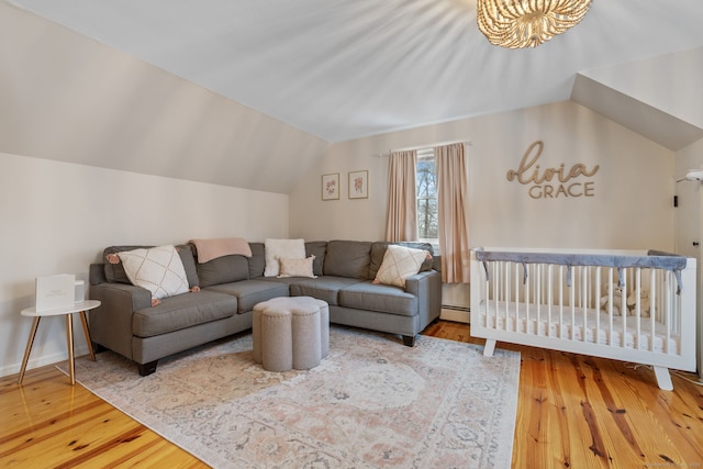 living area featuring hardwood / wood-style floors, a baseboard heating unit, and vaulted ceiling