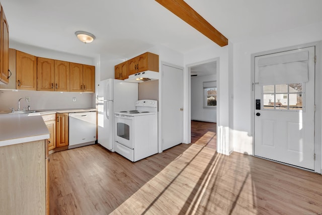 kitchen with under cabinet range hood, a sink, white appliances, light wood finished floors, and light countertops