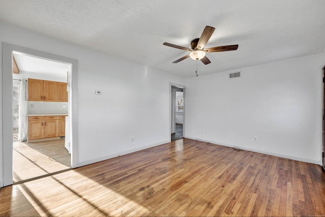 empty room with ceiling fan, visible vents, baseboards, and light wood-style flooring