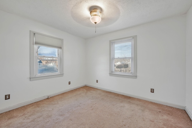 carpeted empty room with a healthy amount of sunlight, baseboards, and a textured ceiling