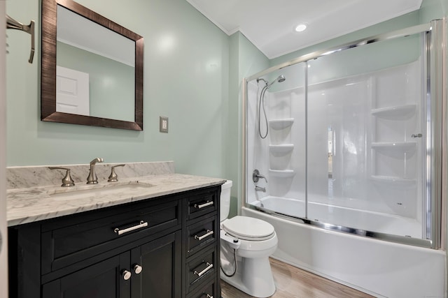 bathroom with combined bath / shower with glass door, toilet, wood finished floors, and vanity