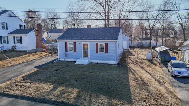 bungalow featuring a front lawn, fence, entry steps, roof with shingles, and a chimney