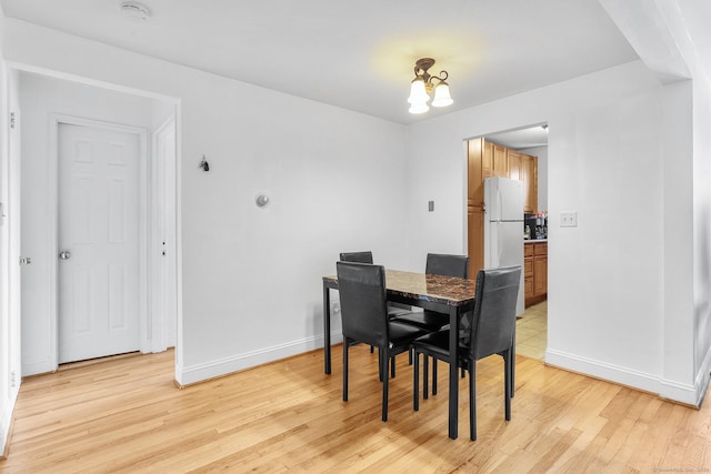 dining space with a notable chandelier, light wood-style floors, and baseboards