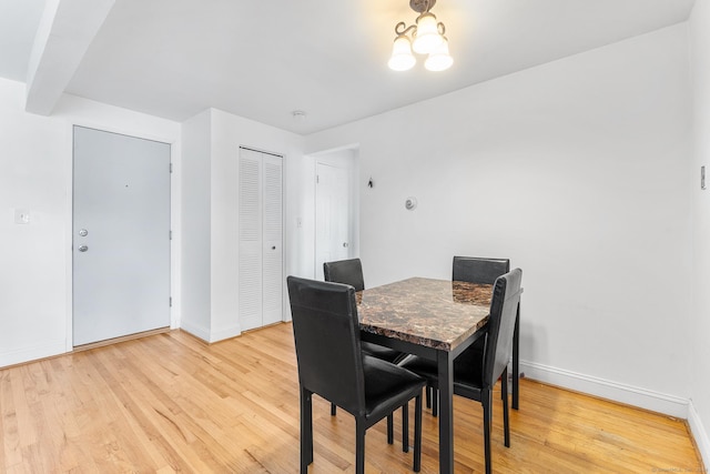 dining space featuring baseboards, a notable chandelier, and light wood finished floors