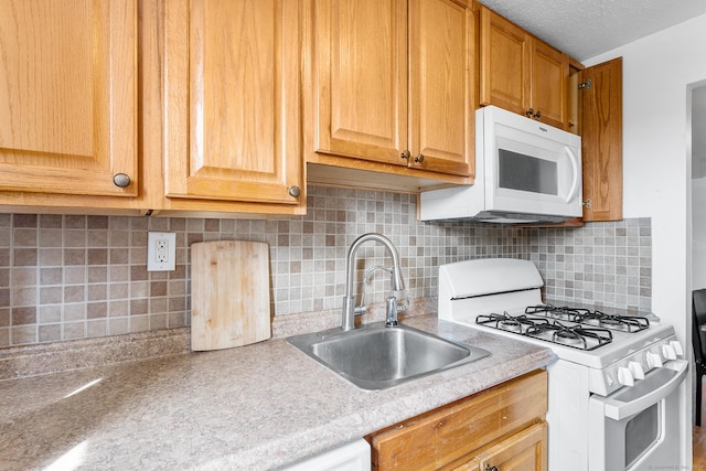 kitchen featuring white appliances, a sink, decorative backsplash, light countertops, and a textured ceiling