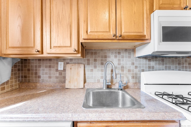 kitchen with a sink, white appliances, backsplash, and light countertops