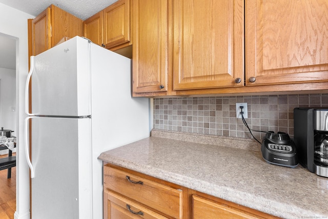 kitchen with backsplash, freestanding refrigerator, and light countertops