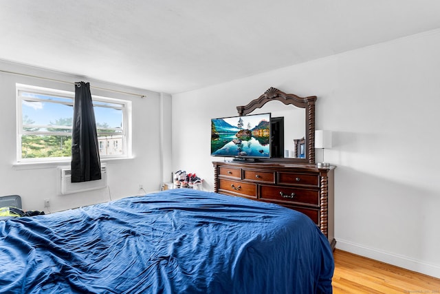 bedroom featuring light wood finished floors, a wall mounted AC, and baseboards