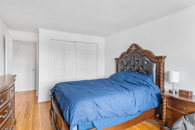 bedroom with crown molding, light wood-style flooring, and a closet