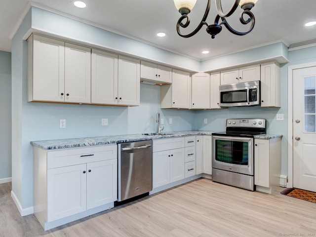 kitchen with light stone counters, recessed lighting, appliances with stainless steel finishes, light wood-style floors, and a sink