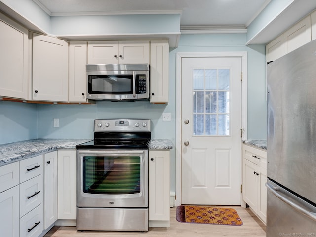 kitchen featuring light stone counters, appliances with stainless steel finishes, ornamental molding, and light wood finished floors