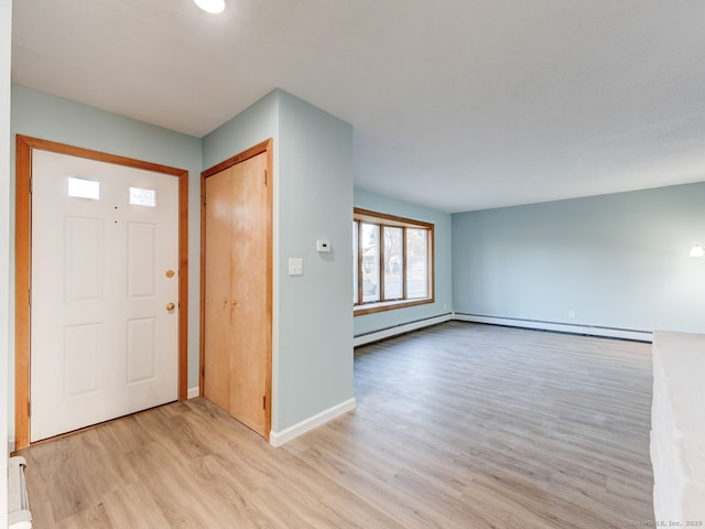 foyer with a baseboard heating unit, baseboards, and light wood finished floors