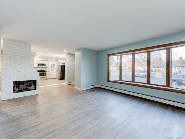 unfurnished living room featuring a baseboard radiator, a baseboard heating unit, a brick fireplace, light wood-type flooring, and a chandelier