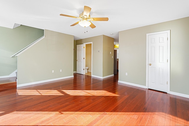 unfurnished living room with stairway, baseboards, ceiling fan, and wood finished floors