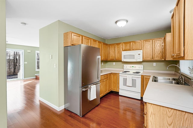 kitchen featuring dark wood finished floors, white appliances, light countertops, and a sink