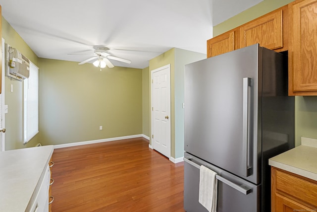 kitchen featuring baseboards, ceiling fan, light countertops, freestanding refrigerator, and wood finished floors