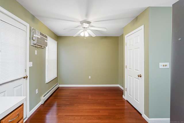 unfurnished room with a ceiling fan, baseboards, dark wood-style flooring, a wall mounted air conditioner, and a baseboard heating unit