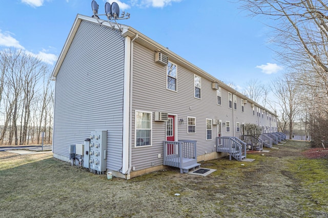 back of property featuring a wall unit AC and a yard