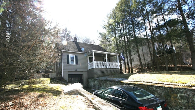 view of front facade with a garage, a shingled roof, and a chimney