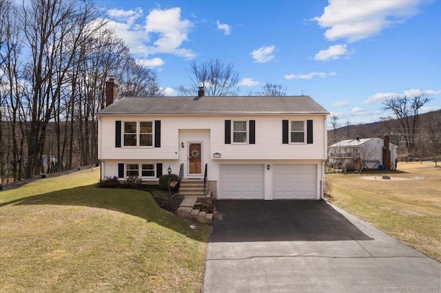 bi-level home with aphalt driveway, a front yard, a chimney, and a garage