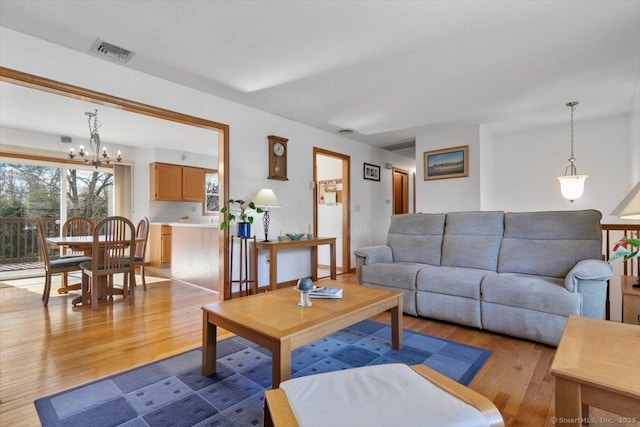 living room featuring a chandelier, visible vents, and wood finished floors