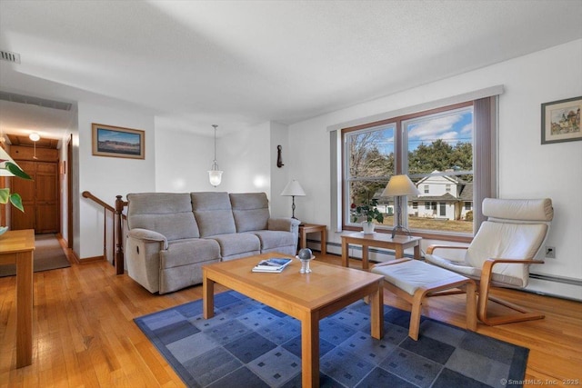 living area with light wood-style flooring, visible vents, a baseboard heating unit, and baseboards