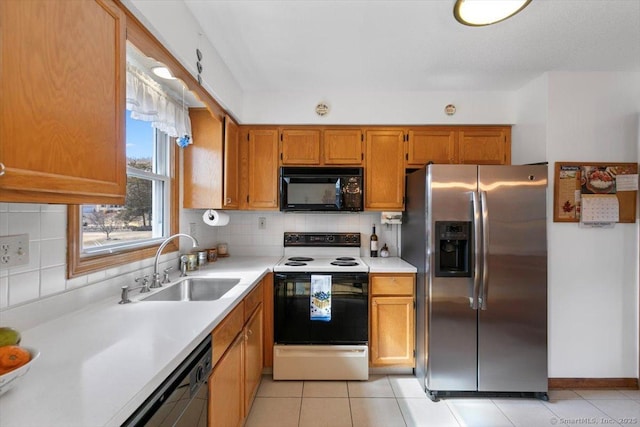 kitchen with black appliances, backsplash, a sink, and light countertops