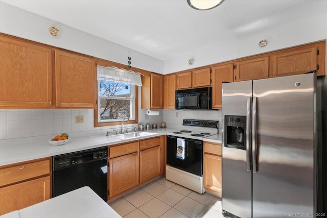 kitchen with light tile patterned floors, a sink, light countertops, backsplash, and black appliances