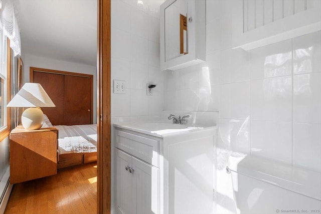 bathroom featuring decorative backsplash, wood finished floors, vanity, and tile walls