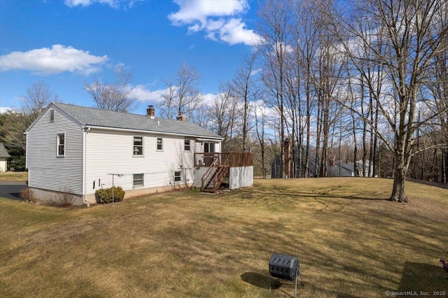 exterior space featuring roof with shingles, a chimney, a lawn, a wooden deck, and stairs