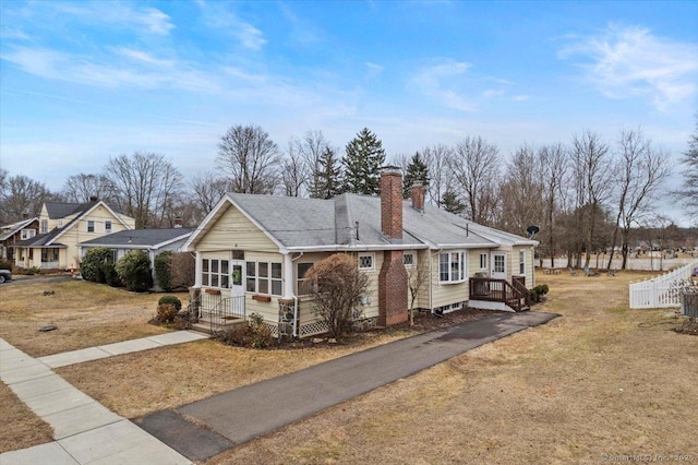 view of front of house featuring a chimney, fence, and a front yard