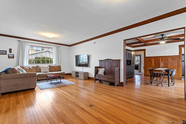 living room featuring coffered ceiling, crown molding, a textured ceiling, light wood-type flooring, and beam ceiling