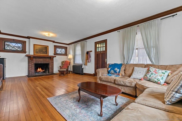 living area featuring radiator, hardwood / wood-style flooring, a fireplace, and crown molding