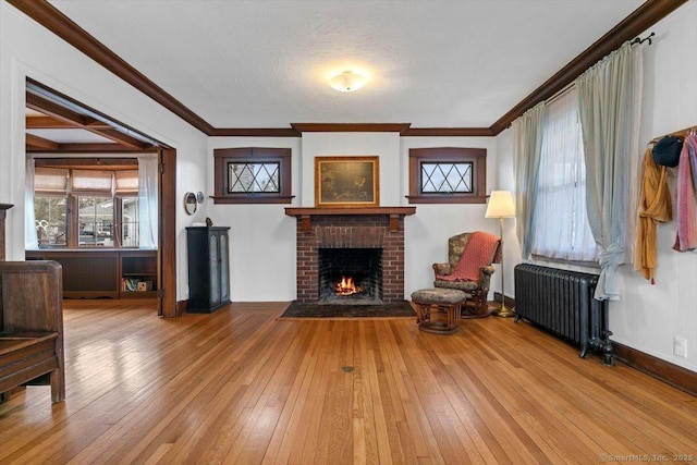 living room with crown molding, radiator, a fireplace, and wood-type flooring