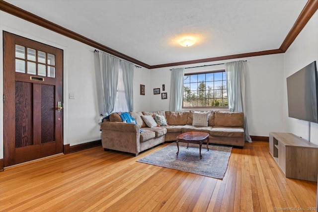 living area with baseboards, crown molding, and light wood finished floors