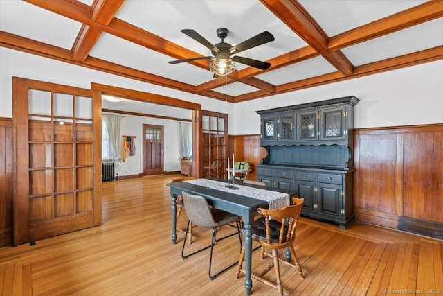 dining area featuring light wood-style floors, radiator, a wainscoted wall, and coffered ceiling