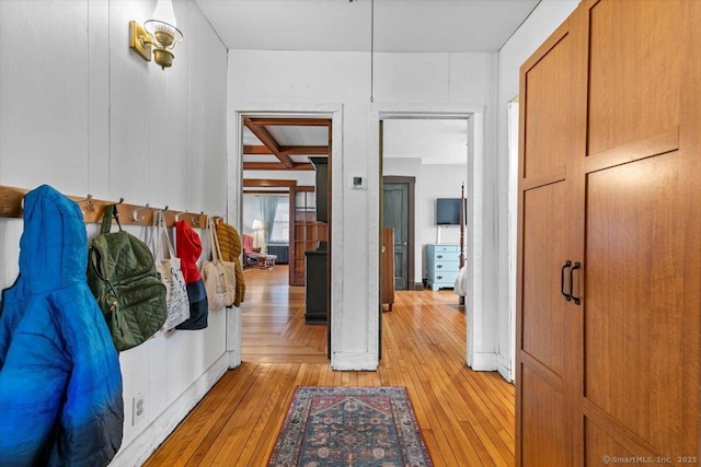 interior space with light wood finished floors, coffered ceiling, and beamed ceiling