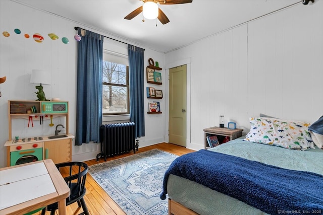 bedroom featuring ceiling fan, light wood-type flooring, baseboards, and radiator