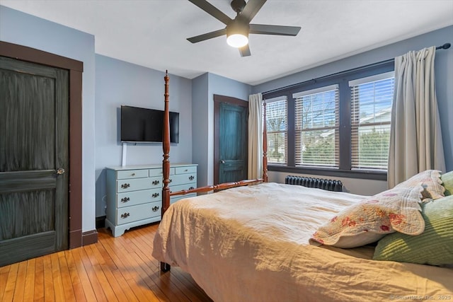 bedroom with a closet, hardwood / wood-style floors, radiator heating unit, a ceiling fan, and baseboards