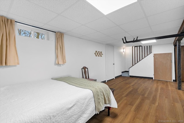 bedroom featuring a drop ceiling and wood finished floors