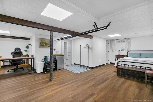 bedroom featuring a drop ceiling, fridge, baseboards, and wood finished floors