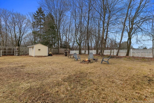 view of yard featuring an outdoor fire pit, a storage unit, a fenced backyard, and an outdoor structure