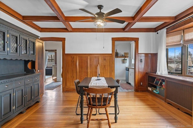 dining area with a wainscoted wall, plenty of natural light, coffered ceiling, and light wood-style flooring