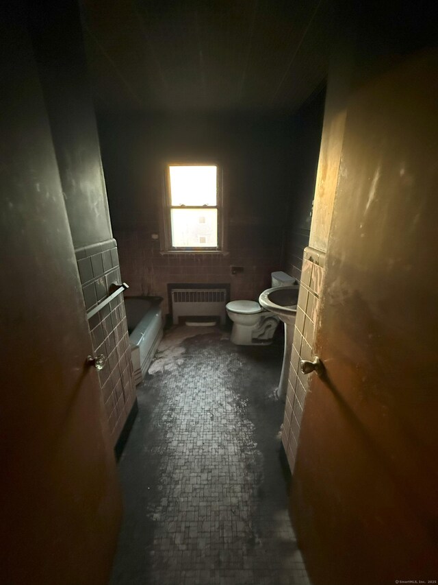 full bath featuring toilet, a tub to relax in, and radiator heating unit