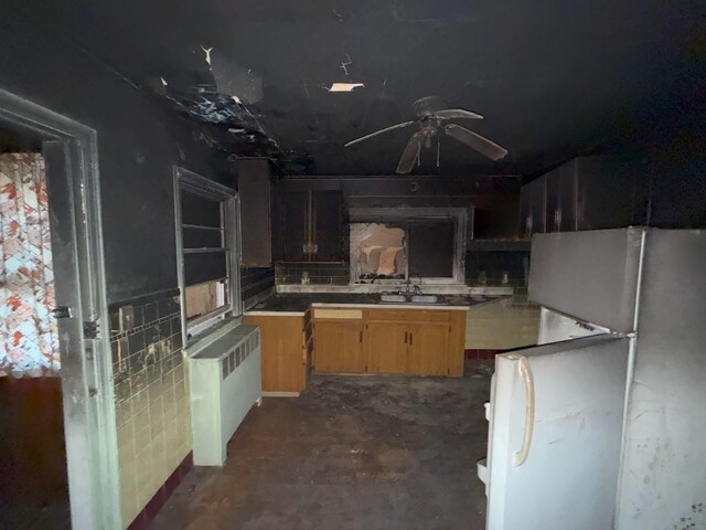 kitchen featuring a sink, freestanding refrigerator, radiator, ceiling fan, and unfinished concrete floors