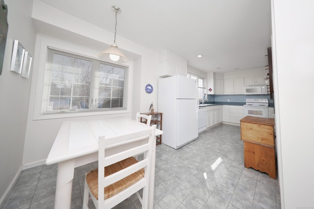 kitchen featuring white appliances, baseboards, recessed lighting, white cabinets, and decorative light fixtures