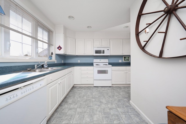 kitchen featuring white appliances, baseboards, a sink, white cabinetry, and dark countertops