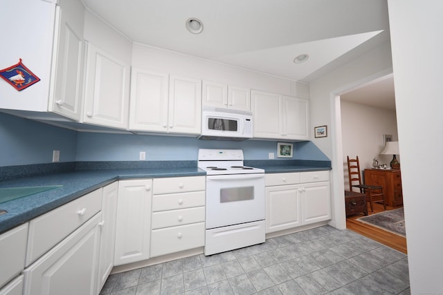 kitchen with white appliances, dark countertops, and white cabinets