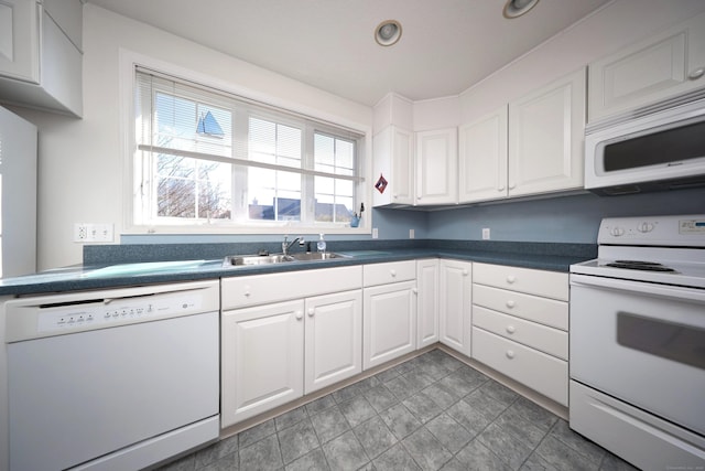 kitchen featuring a sink, white appliances, dark countertops, and white cabinetry